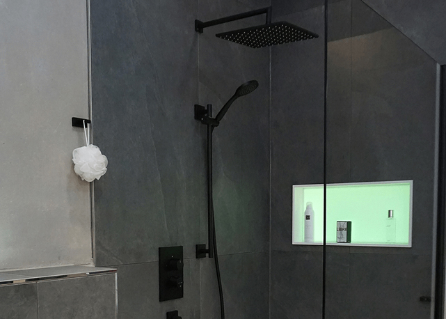 Schwarzer Duschkopf mit Regendusche und Handbrause in moderner Dusche mit beleuchteter Wandnische
